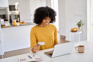 Woman holding a gift card while shopping online on her laptop